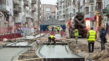 Beton döşeme, yol onarım şantiyesinde birçok işçi ve mikser zaman ayarlarıyla çalışıyor. Tramvay raylarının yeniden inşası
