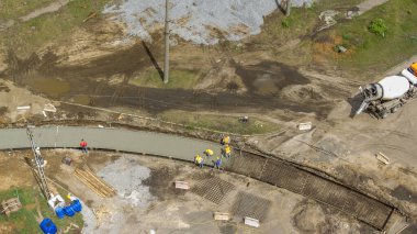 Beton, yol yapımında üniformalı, kazıcı ve mikser makineli birçok işçiyle çalışıyor. Tramvay raylarının yeniden inşası. Eğri yolu olan hava üst görünümü