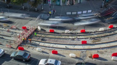 Turuncu inşaat teleskopik mobil vinç kamyon zaman çizgisinden tramvay raylarını boşaltıyor. Şapkalı ve üniformalı endüstriyel işçiler. Evin yakınındaki tramvay raylarının yeniden inşası.