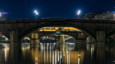 Alacakaranlık sahnesi Ponte Alla Carraia ve Santa Trinita (Kutsal Üçlü Köprü) gece gündüz Arno Nehri üzerinde geçiş zamanı günbatımından sonra suya yansıyan yansımalarla. Floransa, Toskana, İtalya