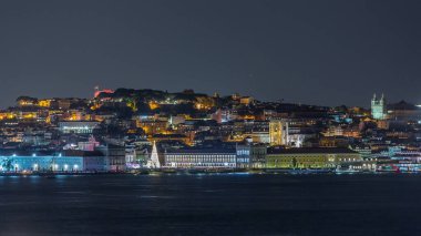 Lizbon Ticaret Meydanı 'nın zaman çizelgesi Noel için aydınlatıldı. Turistler, açılış ışık gösterisi sırasında parlayan ağacın ve dekorasyonların etrafında toplanıyorlar. Portekiz 'in başkentinde gece sahnesi