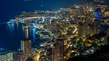 Monako 'nun büyük Corniche yolundan gece geçiş zamanına, Monako Fransa' ya giden hava manzarası. Akşam aydınlatması. Limanın suyundaki yansımalar