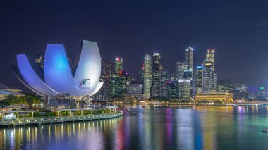 Futuristic architecture flower shape design of the Art Science museum day to night transition timelapse after sunset. Skyscrapers skyline city of Singapore.