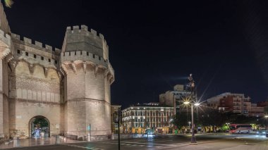 Panorama, Serrans Kuleleri 'nin (Torres de Serranos) Valencia, İspanya' da gece zaman çizelgesini gösteriyor. Şehrin antik duvarlarından gelen büyük bir ortaçağ kapısı. Tarihi bir dönüm noktasının yakınından geçen cadde trafiği