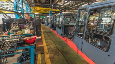 Konveyör montajı, traktörün gövdesini büyük endüstriyel fabrika zaman diliminde sahneleyecek. Kabin montajı, kurulum parçaları özel bir masada.