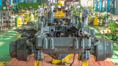 Konveyör montajı, traktörün gövdesini büyük endüstriyel fabrika zaman diliminde sahneleyecek. Çerçeve montajı, Chassis kurulumu ve diğer bölümler etrafındaki işçiler.