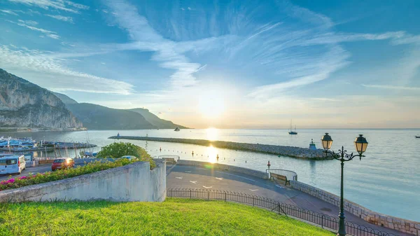 Beaulieu sur mer, Fransa 'dan deniz ve manzaranın gündoğumu panoramik görüntüsü. Tekneler ve yatlar ön planda. Sudaki yansımalar.