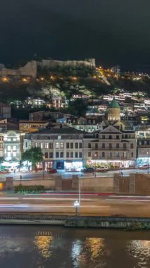 Georgia 'nın Tiflis şehrinde ahşap oymalı balkonları olan renkli geleneksel evler. Aydınlatılmış binalar ve trafik