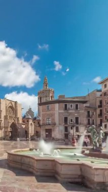 Valencias Plaza de la Virgen 'in panoramik zaman atlaması, Turia Fountain, Cathedral ve Basilica de la Virgen de los Desamparados' un mavi bulutlu gökyüzü altında sergilenmesi