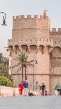 Serrans Kuleleri Torres de Serranos zamanapse Valencia, İspanya 'da. Şehrin antik duvarlarından gelen büyük bir ortaçağ kapısı. İnsanlar gün batımından önce tarihi bir dönüm noktasında köprüde yürüyorlar.