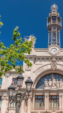 Valensiya 'daki tarihi posta ofisi Palau de les Comunicacions Belediye Meydanı Plaza del Ayuntamiento' da. Süslü cephe, yeşil ağaçlar ve İspanya şehir merkezinde mavi bir gökyüzü..