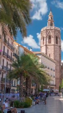 Valencia, İspanya 'daki Plaza de la Reina' nın panoramik zaman çizelgesi. Tarihi bir kilise kulesi, hareketli kafeler ve sıcak Akdeniz bulutlu gökyüzünün altında merkezi bir çeşme..