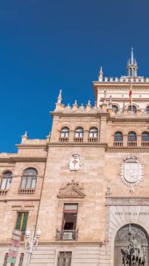 İspanya, Valladolid Plaza de Zorrilla 'daki Süvari Akademisi cephesinden Timelapse. Karmaşık mimarisi olan tarihi askeri bina, bulutlu mavi bir gökyüzünün altında kalabalık bir şehir manzarası ile çevrili..