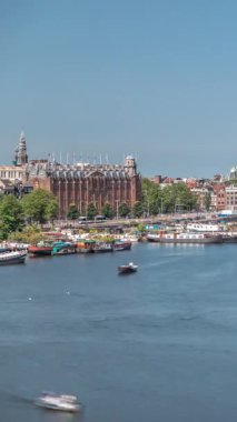 Sudaki pagoda biçiminde bir Çin restoranının hava manzarası, tarihi şehir merkezi binalarının ve nehir kıyısındaki yüzen teknelerin zeminine karşı kurulur. Amsterdam, Hollanda
