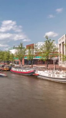 Botlar yüzüyor ve Ulusal Opera Müziği ve Tiyatro Salonu yakınlarından geçiyor. Amsterdam 'daki nehirde bulutlu bir gökyüzünün altında yüzen yüzen evler. Hollanda 'daki popüler turizm beldesi