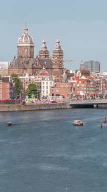 Merkez İstasyonu yakınlarındaki Amsterdam Eski Merkezi 'nde Aziz Nicholas Bazilikası' nın bulunduğu havacılık manzarası. İnsanlar rıhtım boyunca tekne istasyonuyla yürüyorlar. Amsterdam, Hollanda