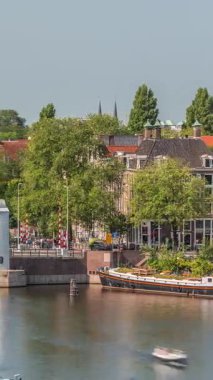 Amsterdam şehri, Montelbaanstoren Kulesi 'nin yer aldığı, kanal boyunca uzanan şehir manzaralı bir zaman çizelgesi. Eski kentteki tarihi Hollanda evleri, köprüler, mavnalar ve yüzen evler