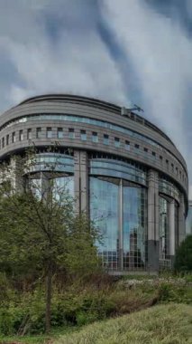 Brüksel 'deki Avrupa Mahallesi' ndeki binalar Avrupa Parlamentosu, Komisyon ve dramatik bulutlu gökyüzü altındaki kurumlarla aynı tarihe denk geliyor. Güneş camdan yansıyor. Leopold Park ön planda çimenlerle