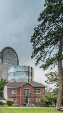 Brüksel 'deki Avrupa Mahallesi' ndeki binalar Avrupa Parlamentosu, Komisyon ve dramatik bulutlu gökyüzü altındaki kurumlarla aynı tarihe denk geliyor. Leopold Park ön planda kırmızı tuğlalı evle