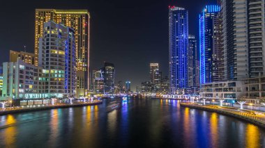 Dubai Marina rıhtımı, Dubai 'deki köprüden gece vardiyasına kadar uzanan kuleleri ve yatları olan Birleşik Arap Emirlikleri. Gün batımından sonra yapay kanallı bölge