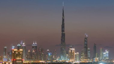 Dubai şehir merkezinin silüeti günden geceye geçiş zamanı. Çölde inşa edilmiş modern gökdelenlerin güzel gökdelenleri. Havaalanı yakınındaki binadan gün batımından sonra hava görüntüsü