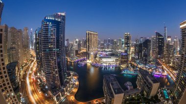 Dubai Marina 'nın gece gündüz aydınlanması. Hava geçiş panoramik zaman dilimi, BAE. Modern gökdelenler ve konut binaları. Yapay kanal şehrindeki alışveriş merkezinin yakınındaki yatlar ve tekneler.