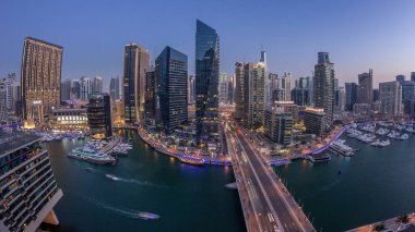 Dubai Marina gezinti güvertesi ve kanalı, gün batımından sonra Dubai, BAE 'de yüzen yat ve teknelerle panoramik hava manzaralı. Modern kuleler ve yoldaki trafik.