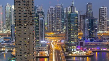 Dubai, Birleşik Arap Emirlikleri güneş battıktan sonra gece geçiş timelapse Dubai Yat Limanı mesire ve kanal kayan yat ve tekne ile günler hava üstten görünüm. Modern kuleleri ve Köprüde trafik