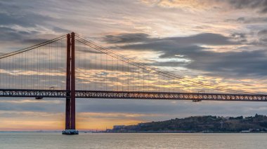 Lisbon city sunrise with April 25 bridge timelapse, River and waterfront early morning. Orange clouds on the sky