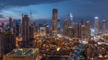 Dubai Şehir Merkezi 'nin ufuk çizgisi günden geceye geçiş zamanı Dubai, Birleşik Arap Emirlikleri' nin tepesinden modern kulelerin panoramik görüntüsüyle. Aydınlatılmış binalar. Çember yollarda ve çeşmelerde trafik