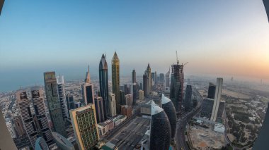 Sheikh Zayed Yolu yakınlarındaki binaların silueti ve Dubai, BAE 'deki hava trafiği gece gündüz değişiyor. Gündoğumundan önce finans merkezinde ve şehir merkezinde modern kuleler ve aydınlık gökdelenler