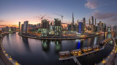 City center at sunset near river with bright illuminated skyscrapers day to night transition aerial timelapse in Business Bay and Downtown, Dubai, United Arab Emirates