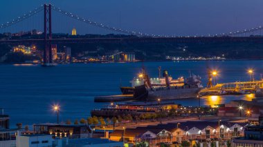 Lizbon ticari limanından geceye geçiş süresi, 25 Nisan Köprüsü, yük vinçli konteynırlar, Lizbon, Portekiz şehir treni. Gün batımından sonra hava görüntüsü