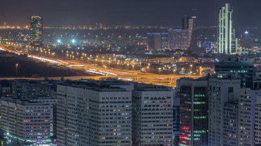Abu Dabi şehir merkezinin havadan silueti, gündüz gece geçiş zamanı, gün batımından sonra akşam trafiğiyle aydınlanan gökdelenlerle.