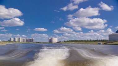 Astana, Kazakistan. Keyif teknesinden Astana 'da Ishim nehrinde hareketli bir seyahat görüntüsü. Mavi gökyüzü ve bulutlarla dolu bir yaz gününde. Bulanık hareket