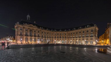 Panorama, Place de la Bourse 'u ve Fransa' nın Bordeaux şehrindeki çeşmeleri gösteriyor. Aydınlatılmış tarihi binalar büyük meydanın sınırında. Trafik ve sokakta hareket sahneyi güçlendirir