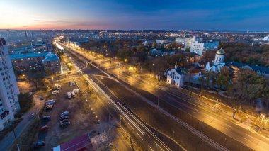 Yol trafiği olan hava manzarası günden geceye geçiş panoramik. Günbatımından sonra yeni inşa edilen Moskova Bulvarı ve yerleşim bölgeleriyle yukarıdan Kharkiv şehri