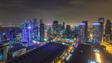 Batı Körfezi bölgesinin ufuk çizgisi Doha 'da günden geceye geçiş zamanı, Katar. Günbatımından sonra modern gökdelenlerin çatıdan görünüşü aydınlandı. Yolda trafik vardı.