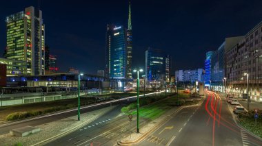 Günbatımından sonra Milano 'nun Milano kentinde, Porta Nuova iş bölgesindeki modern gökdelenleri ile birlikte gece ve gündüz geçiş panoramiklerini görüyoruz. Yollarda trafik vardı. Pencerelerde ışık var. Köprüden üst görünüm