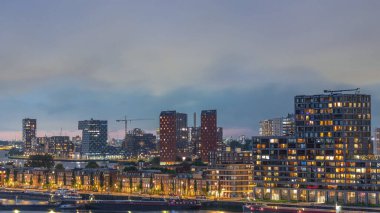 Rotterdam, Hollanda 'daki Katendrecht Yarımadası ve Maashaven Limanı' nın panoramik hava ve gece geçiş zamanı. Şehir silueti modern gökdelenler ve geleneksel Hollanda rıhtım evleri