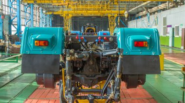 Konveyör montajı, traktörün gövdesini büyük endüstriyel fabrika zaman diliminde sahneleyecek. Çerçeve montajı, arka ışıklar kurulu ve diğer bölümler.