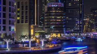 Dubai Marina rıhtımı kuleleri, rıhtımda restoranları ve Dubai 'deki köprüden geceye geçiş zamanı, Birleşik Arap Emirlikleri. Gün batımından sonra yapay kanallı bölge