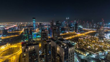 Günbegün modern şehrin hava manzarası trafik ve aydınlık gökdelenler ile geçiş zamanı, günbatımından sonra ofis binaları. İş Körfezi, Dubai, Birleşik Arap Emirlikleri.