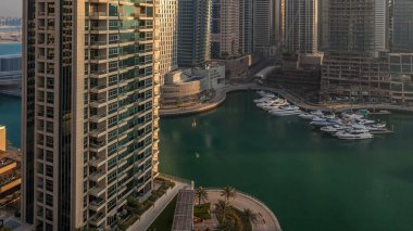Modern gökdelenler ile Yatlar Dubai, Birleşik Arap Emirlikleri Dubai Marina gündoğumu ışıklar timelapse parlayan bir bakış. Camına yansıyan ışık ışınları.