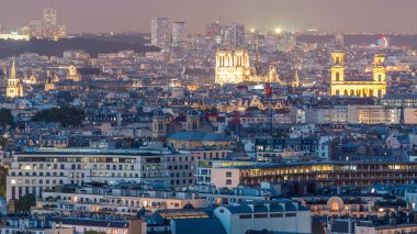 Paris 'teki evlerin çatılarının üstündeki hava panoraması gece gündüz geçiş zamanı. Notre Dame de Paris 'in akşam manzarası ve Saint-Sulpice gün batımından sonra aydınlandı.