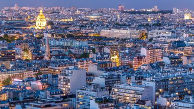 Paris 'teki evlerin çatılarının üstündeki hava panoraması gece gündüz geçiş zamanı. Günbatımından sonra aydınlanan gece manzarası, kiliseler ve diğer manzaralar.