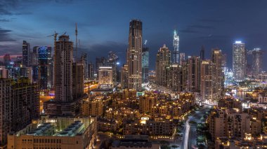 Dubai Şehir Merkezi 'nin ufuk çizgisi günden geceye geçiş zamanı Dubai, Birleşik Arap Emirlikleri' nin tepesinden modern kulelerin panoramik görüntüsüyle. Aydınlatılmış binalar. Çember yollarda ve çeşmelerde trafik