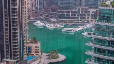 Dubai Marina 'daki rıhtım güvertesi gece gündüz geçiş zamanı. Kanalda yüzen tekne ve yatlar. Dubai, Birleşik Arap Emirlikleri