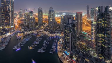 Dubai Marina'nın havadan üstten gündüz geceye geçiş saati. Dubai, Bae gün batımından sonra yüzen yatlar ve tekneler ile gezinti ve kanal. Işıklı modern kuleler ve yolda trafik