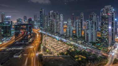 Business Bay, Dubai, Uae 'de birçok gökdelenden geceye geçiş süresine sahip konut ve ofis kompleksi. Körfez Bulvarı Parkı 'nın yanındaki büyük otoparkta arabalar ve trafik vardı.
